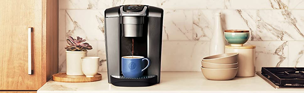 sleek modern kitchen bench with a black coffee machine pouring coffee in a blue mug