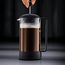 How to make coffee in a French Press with a hand pushing down the plunger on a glass press.