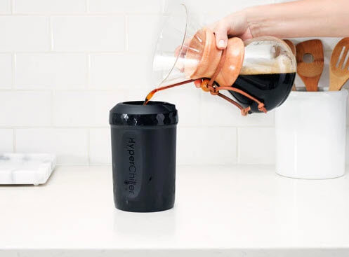 A hand pouring a glass carafe of coffee into a Hyperchiller V2 Cold Brew Iced Coffee Maker