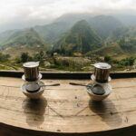 2 Cups of Vietnamese Coffee sitting on a wooden bench overlooking the mountains, this shows one of the many reasons why Vietnamese coffee is best