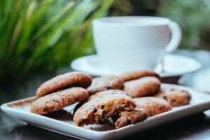 Milk cookies served with coffee, chocolate chip cookies, coffee in the background