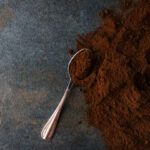 Old Coffee Grounds on a grey surface with a silver teaspoon