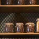 Some mason jars full of coffee beans sitting on a wooden shelf