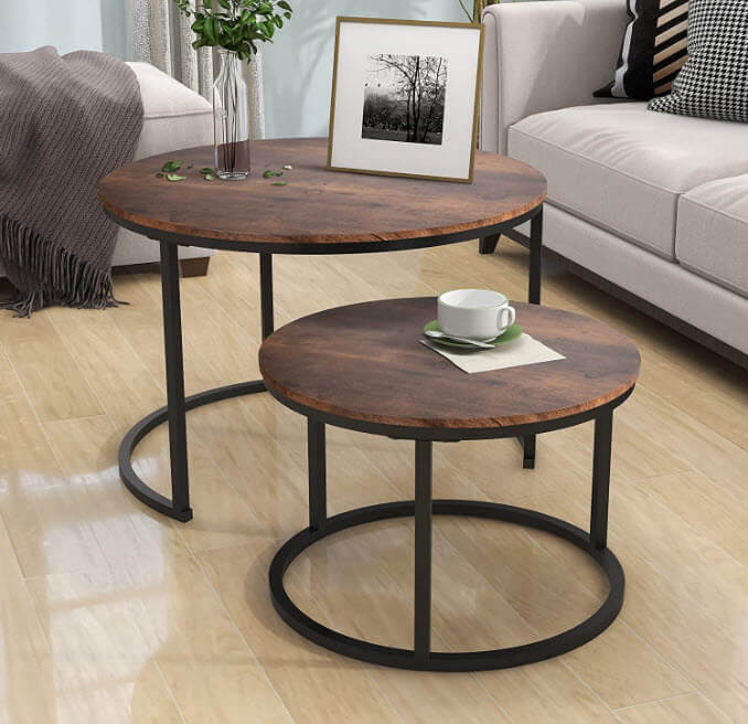 2 round wooden coffee tables with black stands and a cup, photo and vase on top