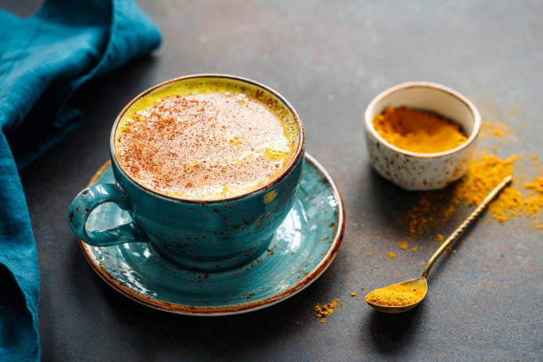 Closeup view of turmeric latte cup on a textured dark background.