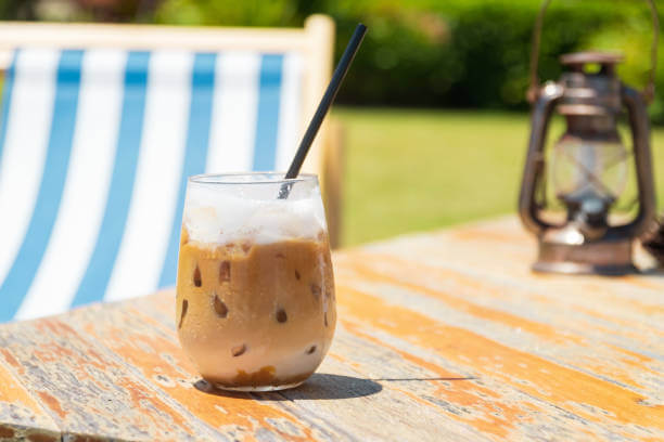 Iced coffee on wooden table on summer beach.