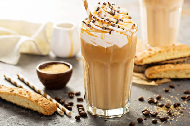 Iced caramel latte coffee in a tall glass with syrup and whipped cream