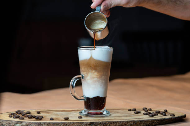 Latte macchiato with whipped cream and caramel sauce in tall glass