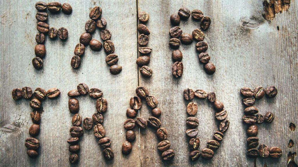 Fair Trade written in coffee beans on a rustic wooden surface.