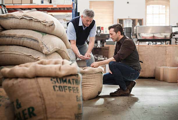Male owner of a coffee roasting business talking with one of his workers. 