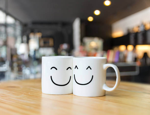 Two white happy cups on coffee store blur background,