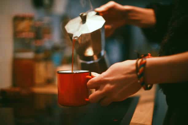 Close-up of a young woman's hands while she's pouring coffee.