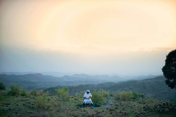 Wide view of One Woman performing a Traditional Coffee Ceremony on a hillside at sunset outside Lalibela Ethiopia Horn of Africa