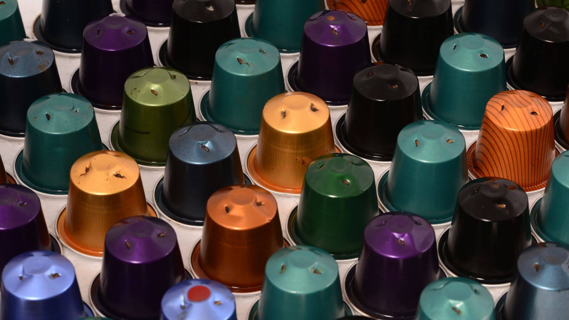 Rows of different colored used coffee pods.