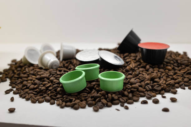Coffee Pods of Various Shapes, Sizes and Colors Placed on Top of Roasted Coffee Beans.
