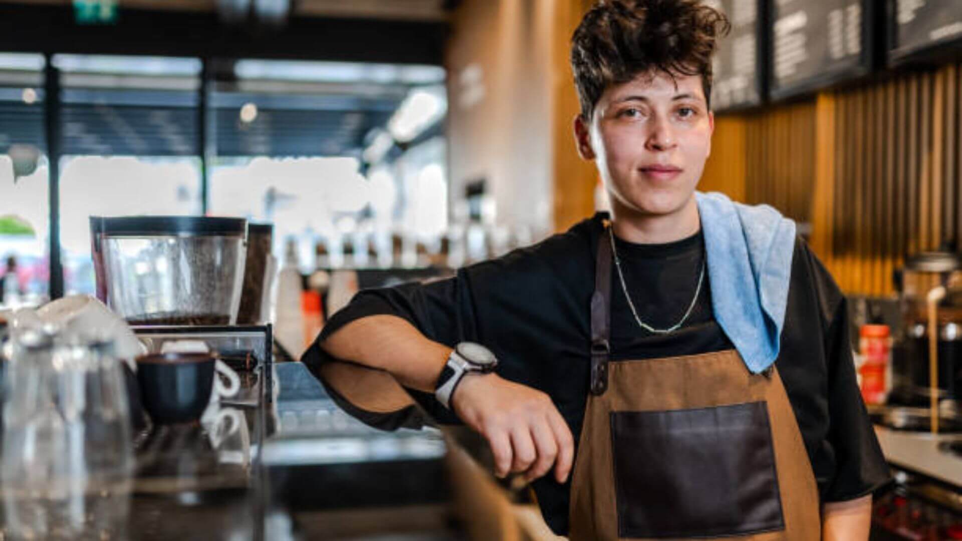 Smiling barista ready to prepare drink in coffee bar