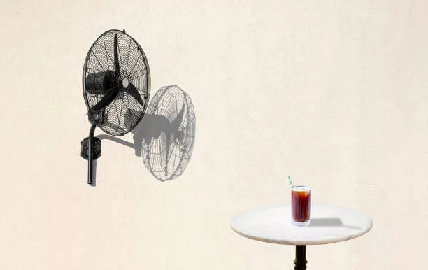 Iced americano on table. Fan on white wall