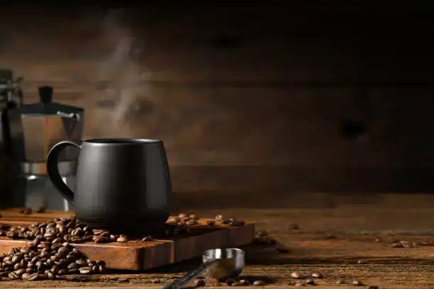 Cup of coffee with smoke and coffee beans on old wooden background. Moka pot and coffee cup. Moka pot and coffee cup