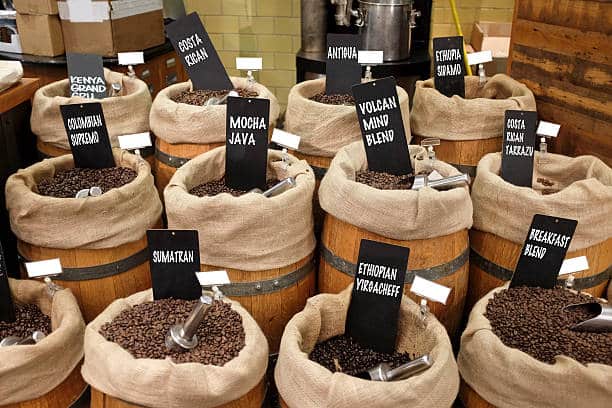 Coffee beans from around the world with name tags, inside barrels.
