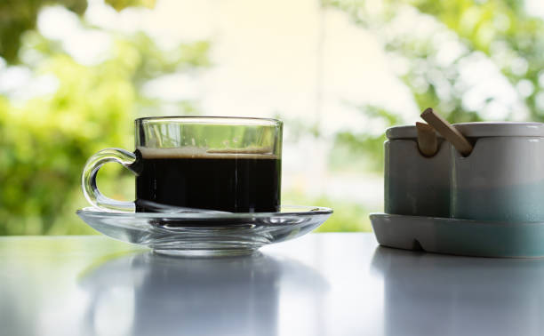 Glass of americano fresh made dark black strong coffee on wooden board table in morning.