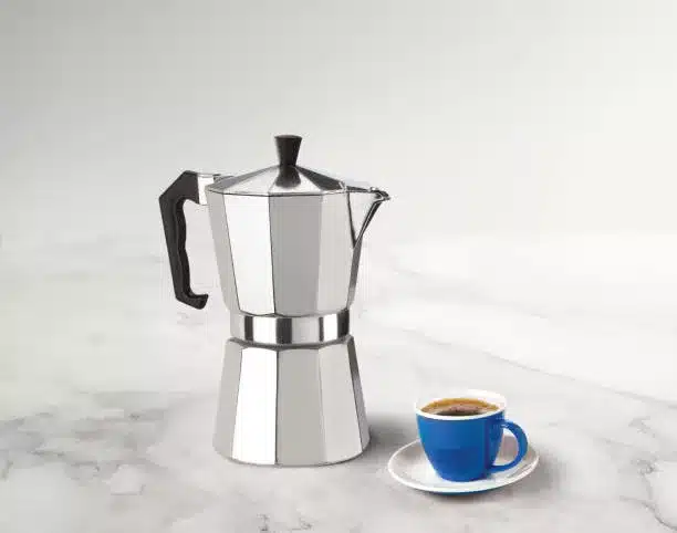 Bialetti stovetop espresso maker with a coffee cup on a marble countertop