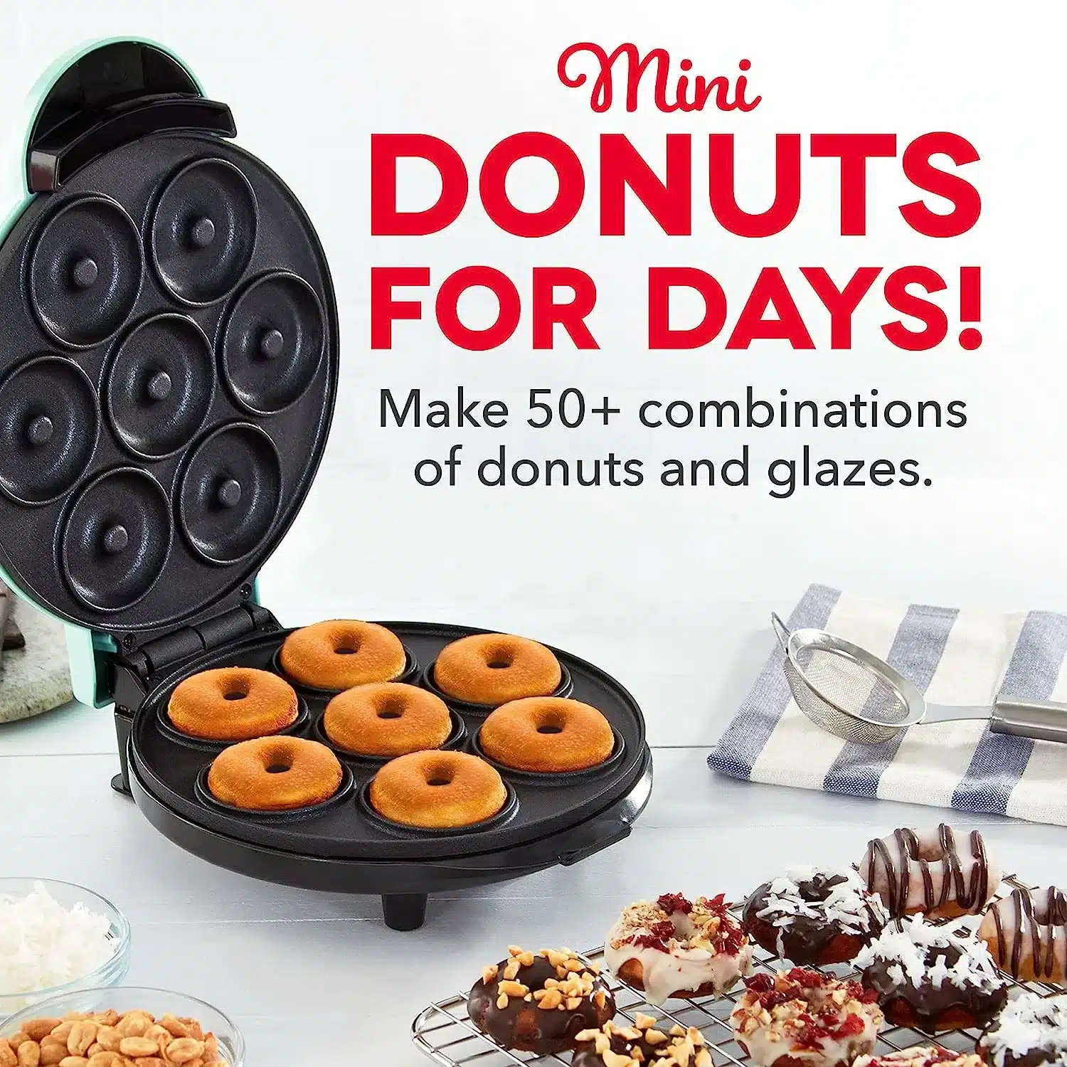 A black mini donut maker filled with cooked donuts. A tray of decorated donuts sits on a rack ready to eat.