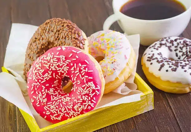 Four sprinkle donuts and a cup of coffee