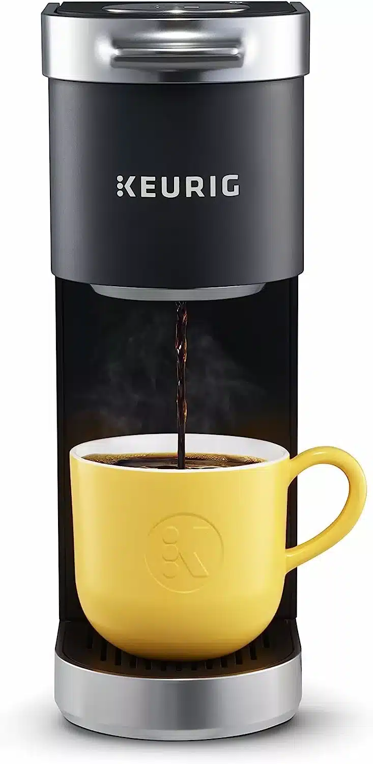 Black and silver single cup coffee maker with a yellow mug and black coffee pouring into the mug.