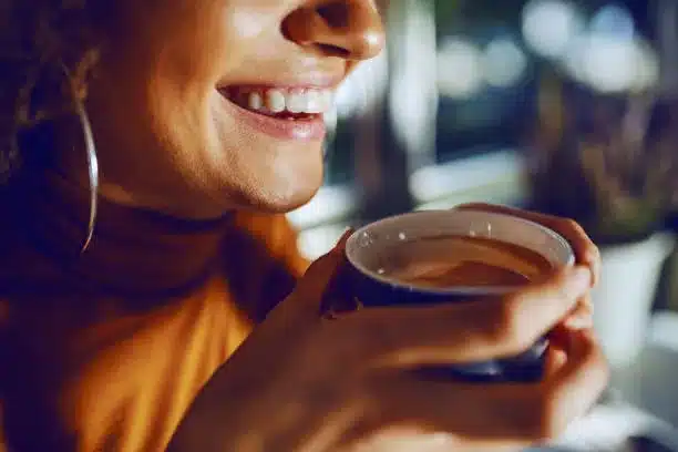 Close up of mixed race smiling woman holding coffee.
